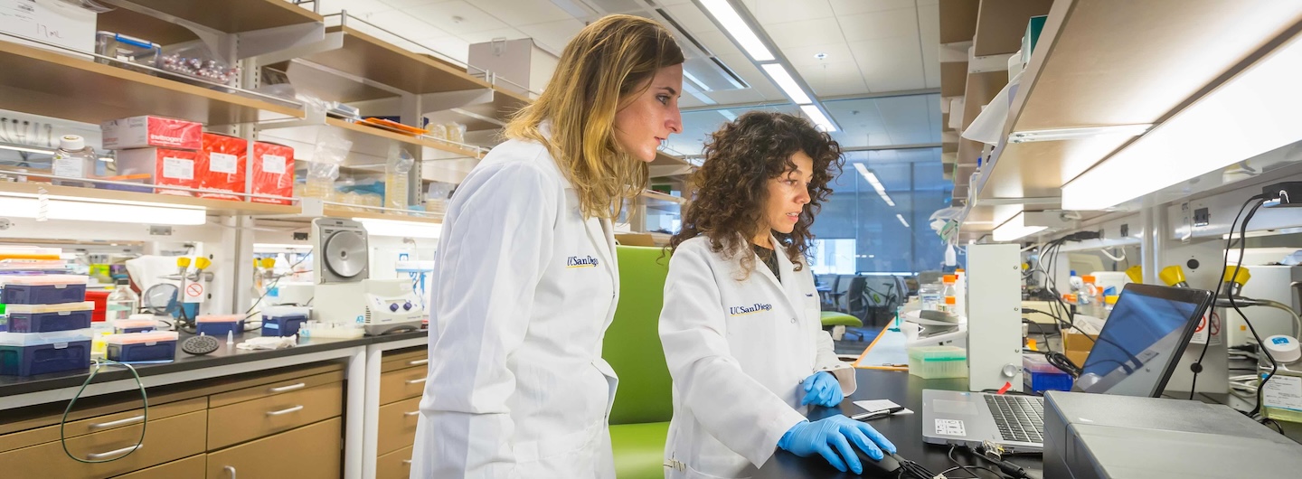 two physicians with white lab coats facing each other walking outside 